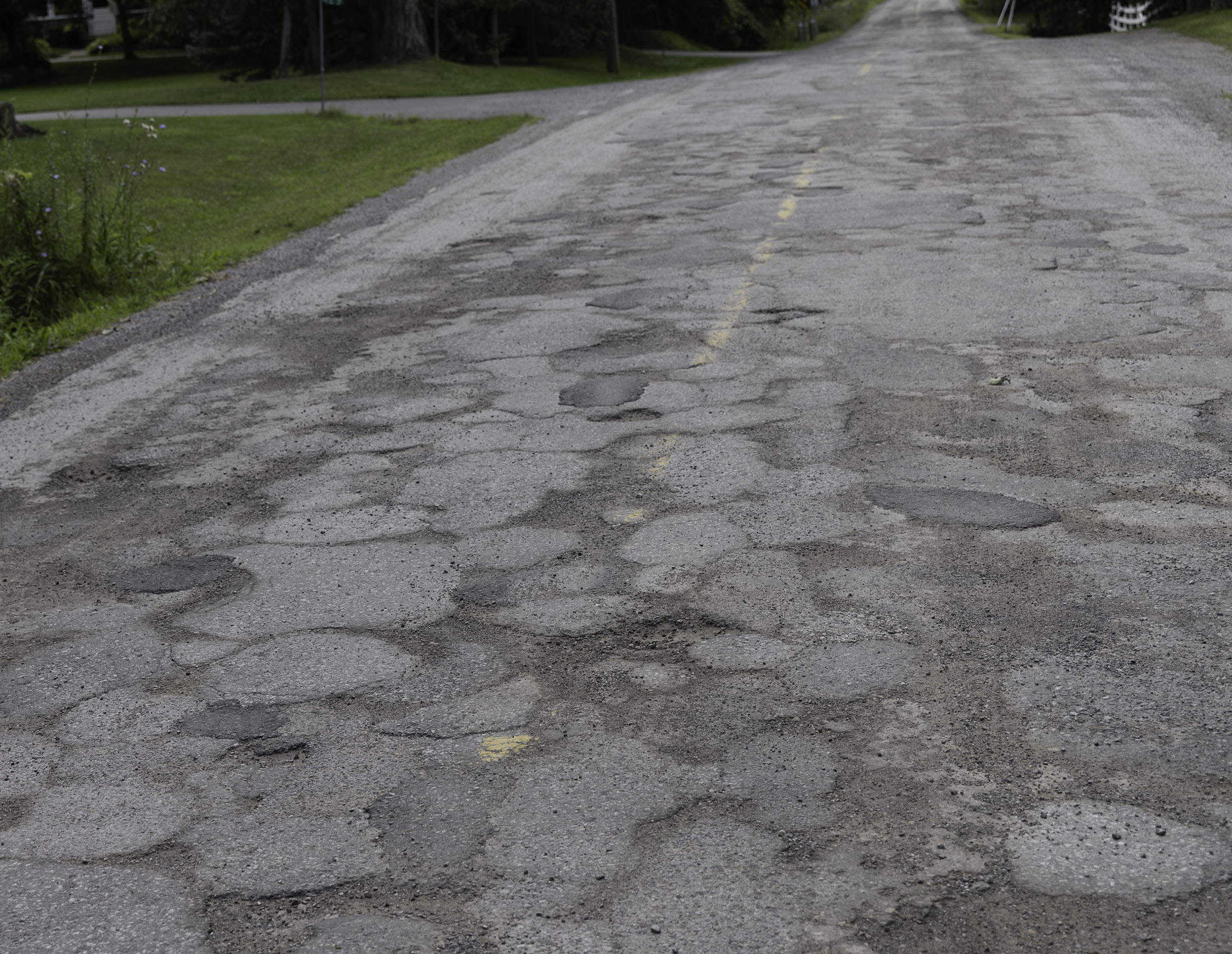 Cracked and patched pavement on Third Concession Road running through Cherrywood